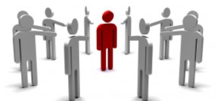 Artículo del blog sobre Acoso Laboral Una figura roja en el centro rodeada de figuras grises que parecen hablar por altavoces.