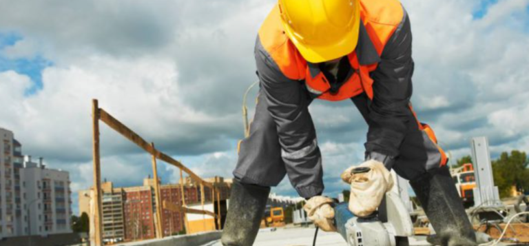 Artículo del blog sobre falsos autónomos Trabajador de la construcción usando una herramienta en un sitio de obra.