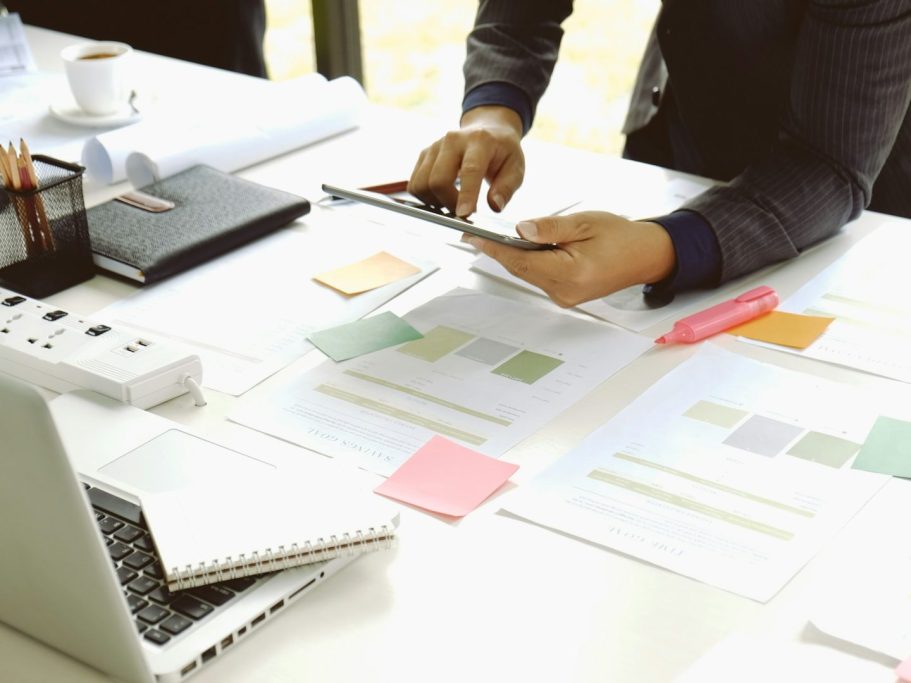 Más de seguridad social Mano utilizando un teléfono en una mesa con documentos y un ordenador portátil.